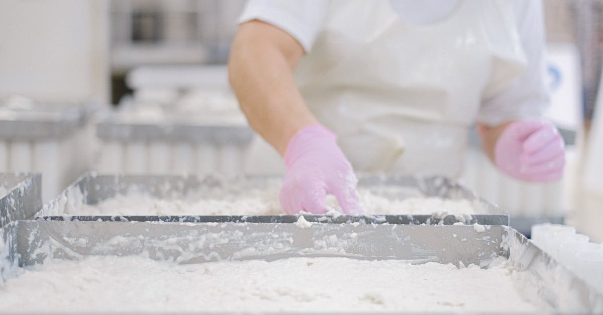 close up of a worker processing dairy products wearing gloves and an apron