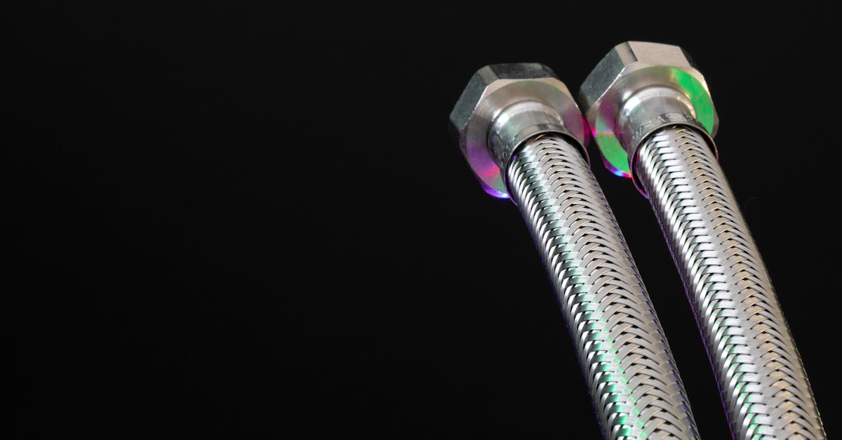 close up of metal flex pipes with hex nuts on a black background showcasing industrial design