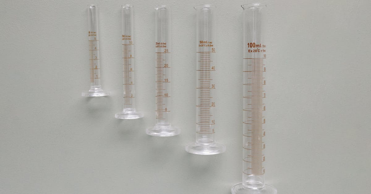 collection of measuring cylinders lined up against a neutral background in a lab