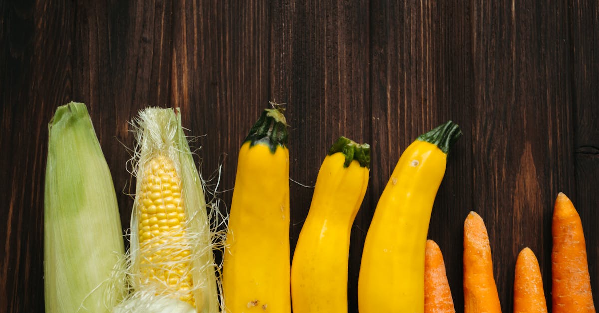 colorful fresh corn zucchini and carrots arranged on a rustic wooden background