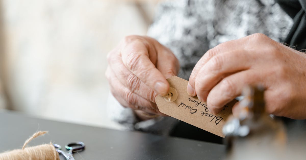 detailed view of hands attaching a handmade gift tag with jute string emphasizing craftsmanship