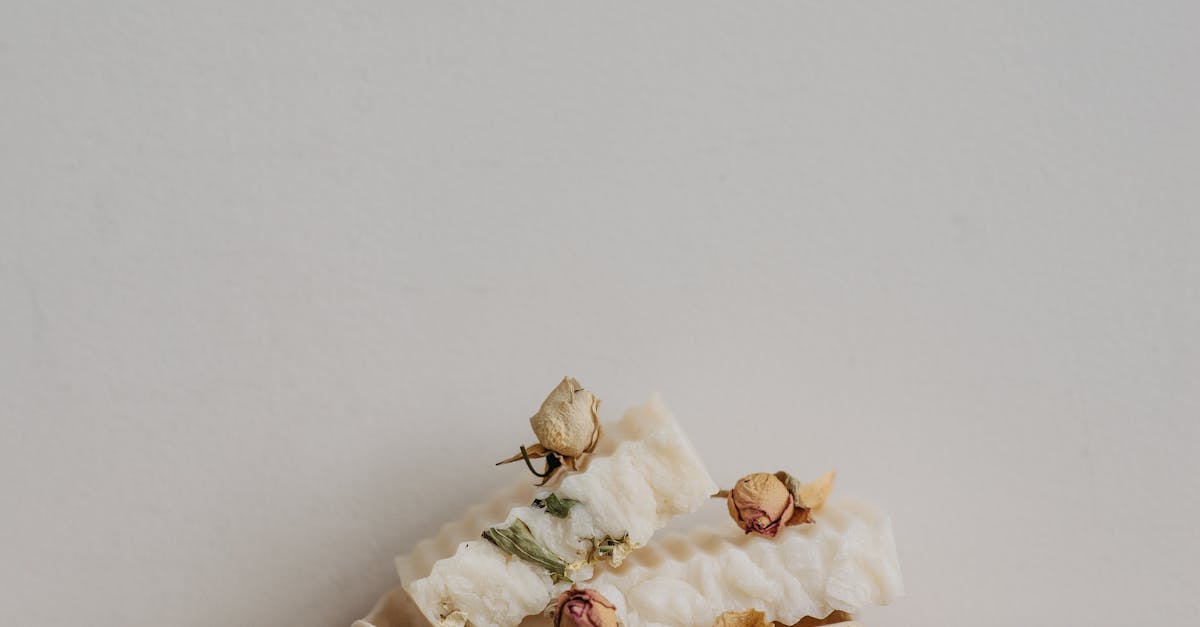 eco friendly white soap bars with dried flowers on a ceramic tray perfect for sustainable living