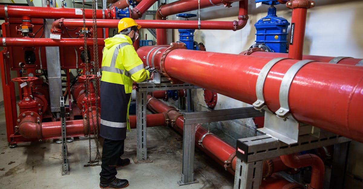 engineer with safety gear inspecting red industrial piping system indoors 1