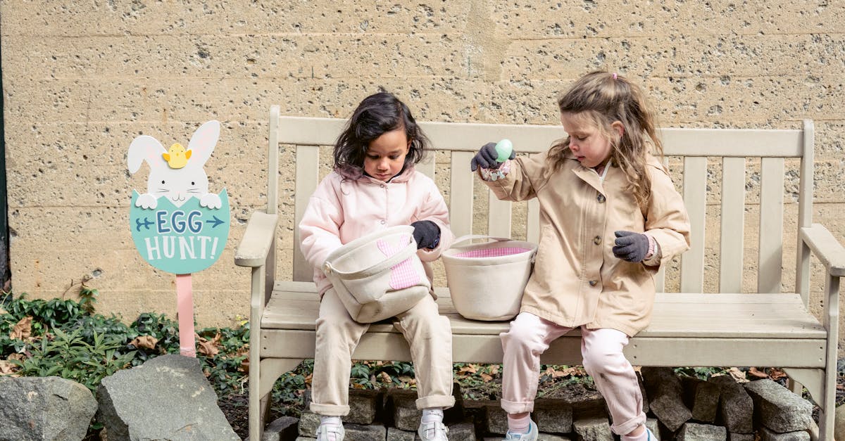 full body positive cute diverse girls in warm clothes playing with easter eggs and sitting on bench