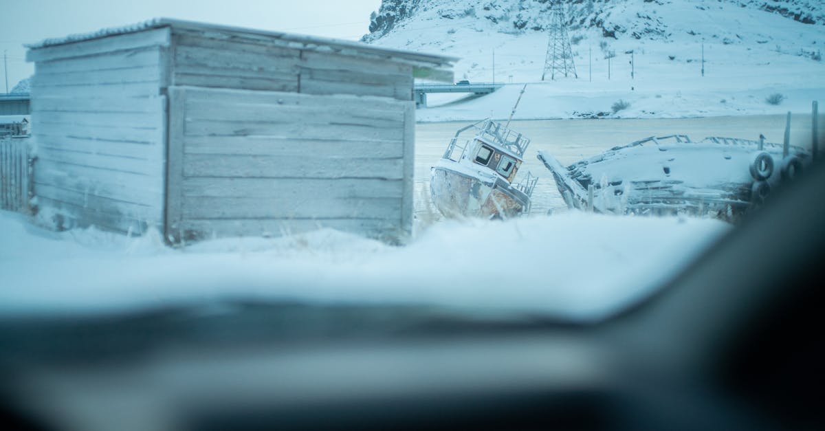 icy scene with boats and a shed in a snow covered landscape
