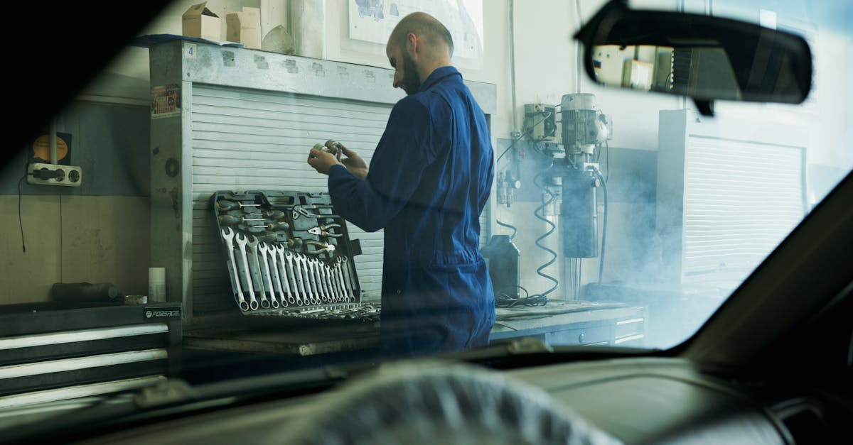 mechanic in blue overalls working with tools in a smoky garage workshop