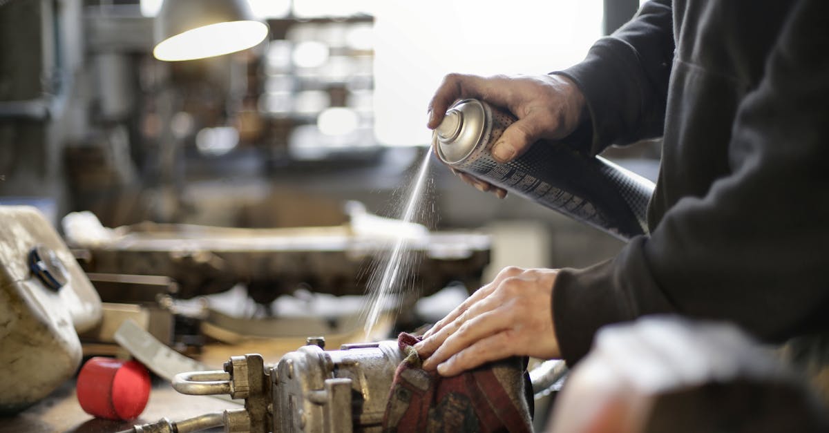 person cleaning machine part with spray can in workshop environment