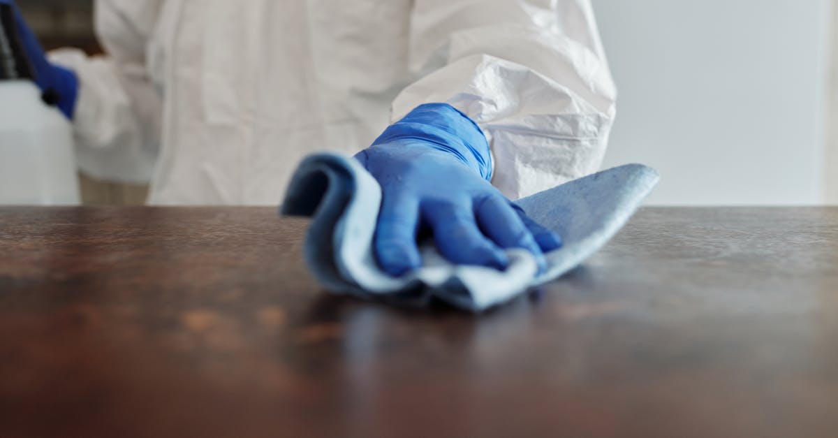 person in protective suit using disinfectant on surface to ensure cleanliness and safety