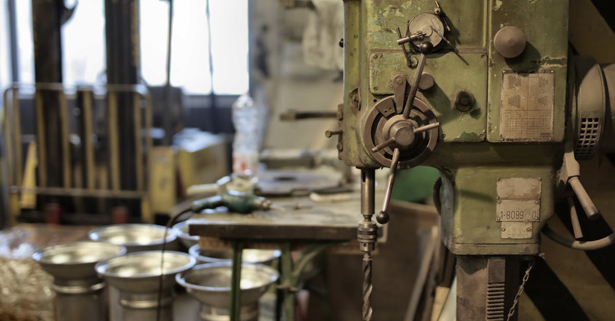 side view of industrial drilling machine with green casing situated in deserted workshop