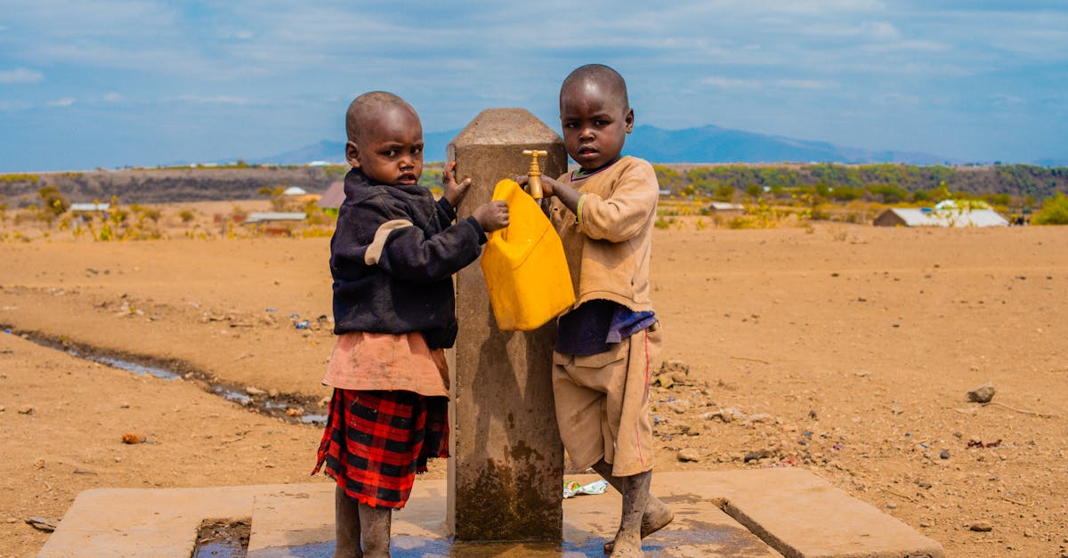 two children filling a container at a rural water tap on a sunny day 1
