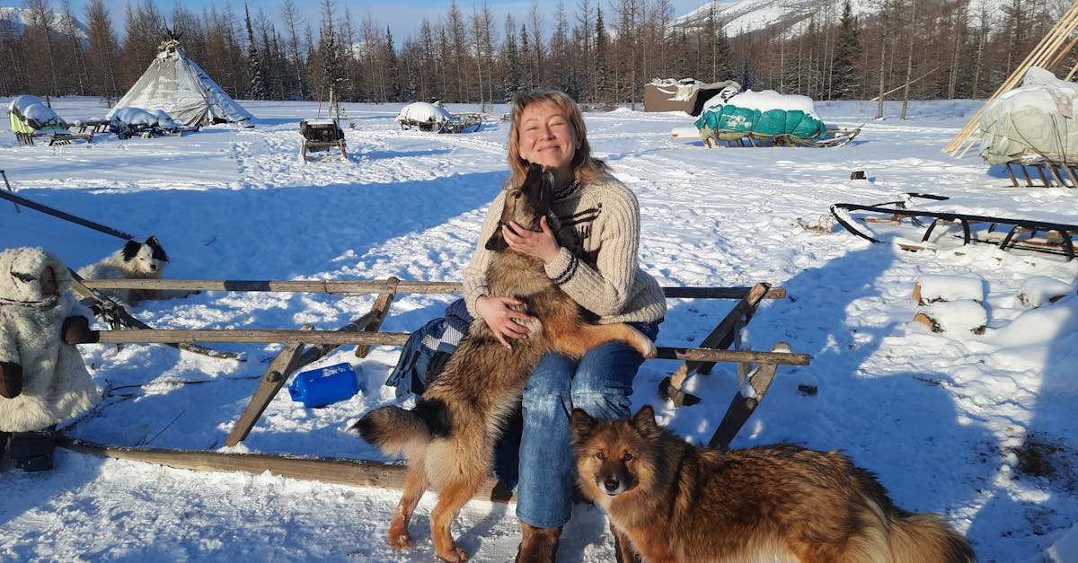 woman enjoying winter with dogs in a scenic snowy outdoor environment showcasing affection and comp