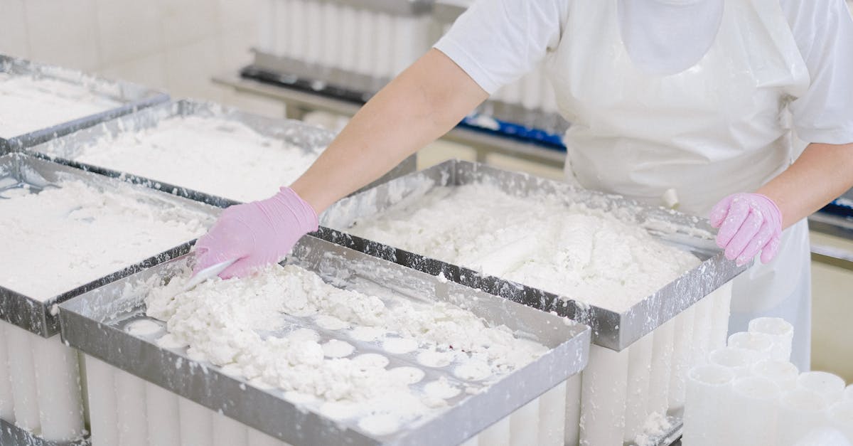 worker in protective gear handling cheese curds in an industrial dairy setting